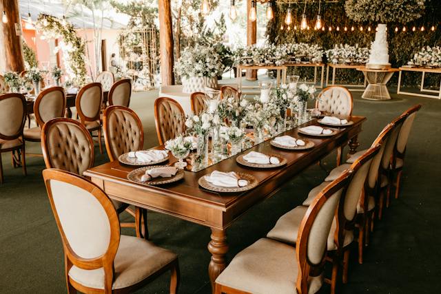 Un lugar de celebración con mesas, sillas y flores preparadas para una boda.