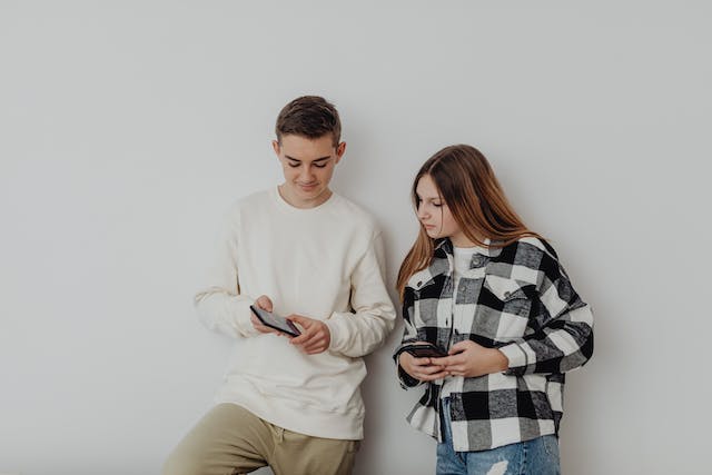 Dois adolescentes a olhar para influenciadores das redes sociais nos seus telemóveis.