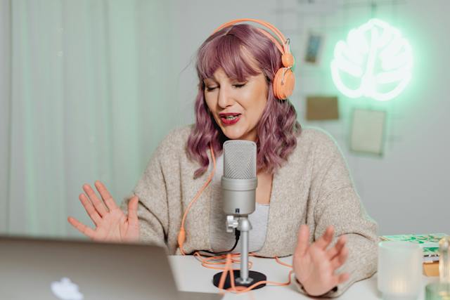 Een jonge vrouw met roze haar die haar mening geeft tijdens een podcast die ze later op sociale media zal plaatsen.