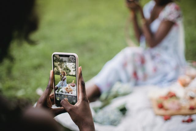 Una donna che scatta una foto esteticamente gradevole a una influencer all'aperto.