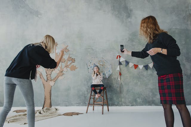 Zwei Frauen nehmen ein Video von einem Fotoshooting für ein Kind auf.