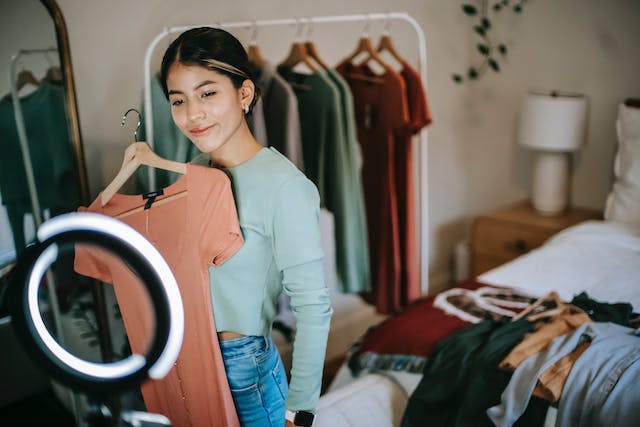 Una joven graba un vídeo probándose ropa de su marca de moda favorita.