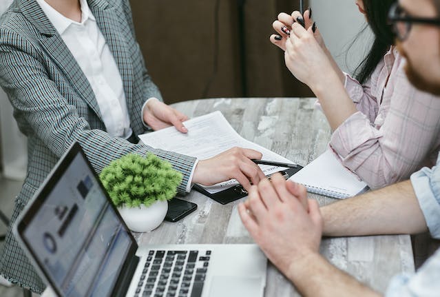 A group of people in an office signing a contract during a meeting.