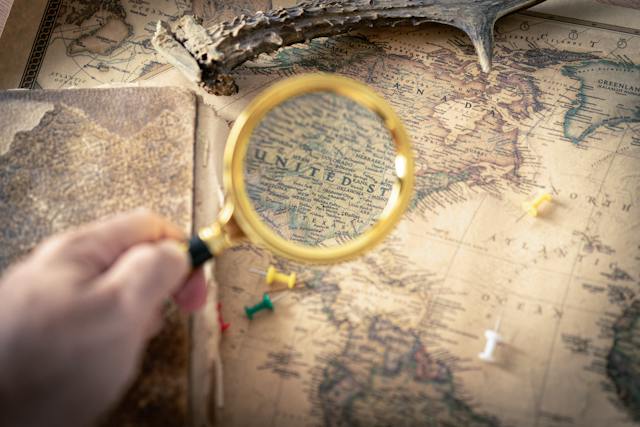 Someone holding a magnifying glass to take a closer look at the U.S. map