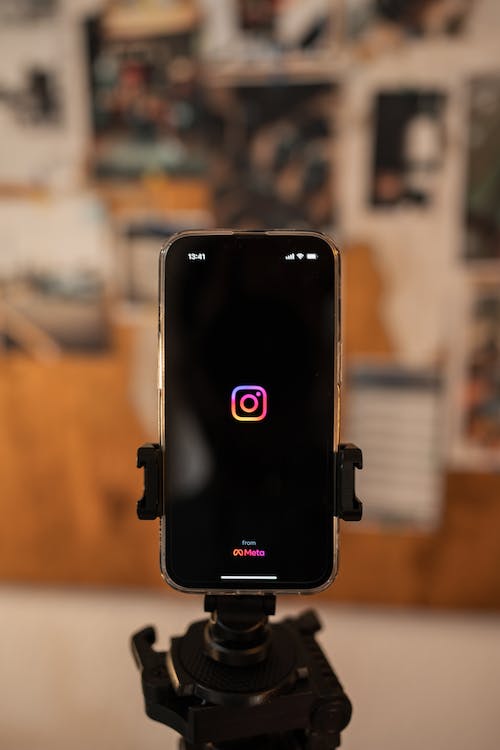 A person is opening the Instagram App on a phone stand. 