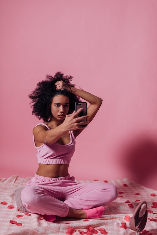 A hair influencer creates a reel while holding her hair.