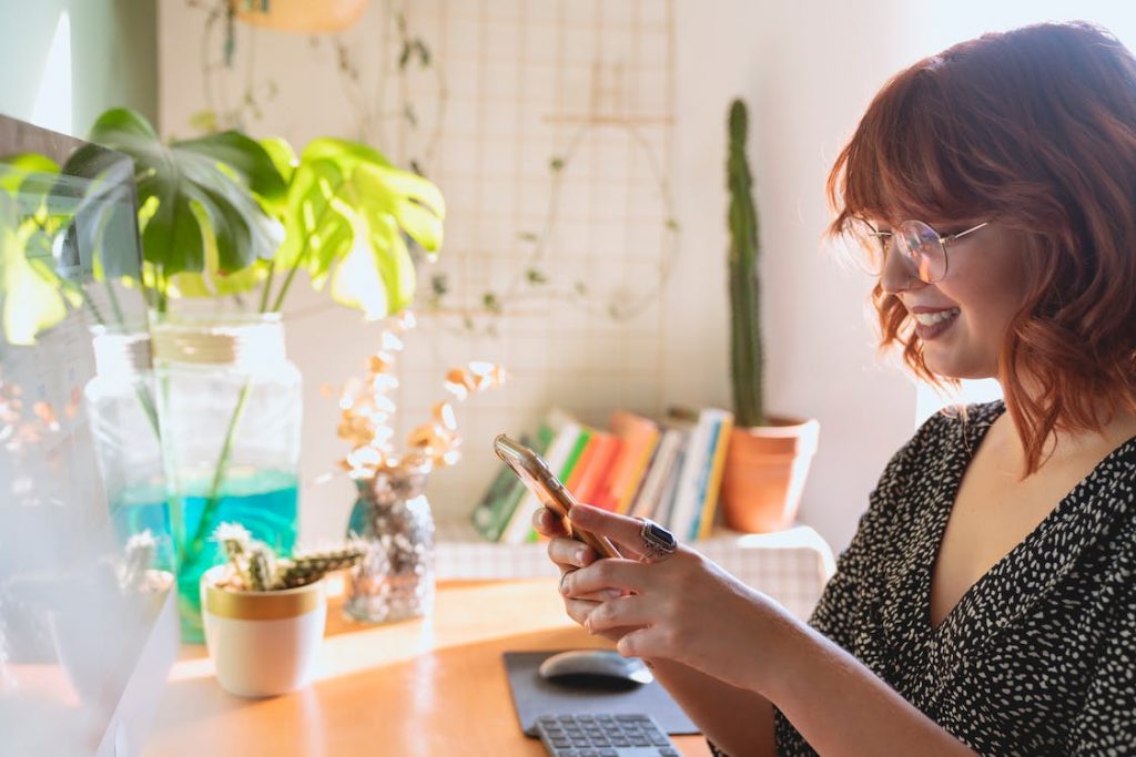 ノートパソコンの前で携帯電話を持ち、ソーシャルメディア戦略を練っている人がいる。