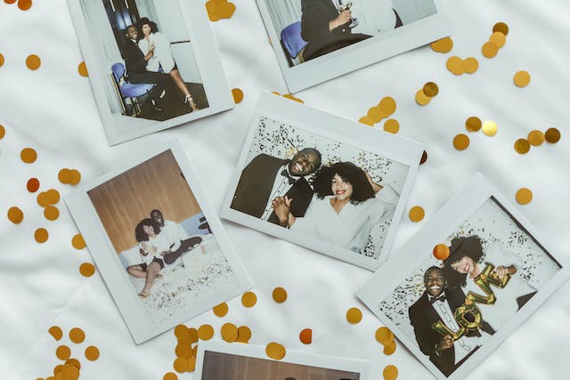 Polaroid photos of a happy couple laid out on a white cloth with gold confetti.
