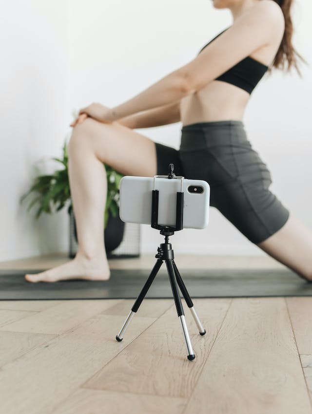 Una mujer grabando un vídeo de sí misma haciendo su rutina de yoga.