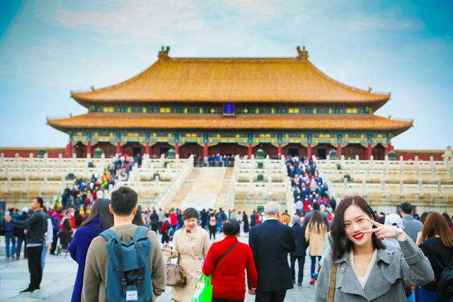 Una donna cerca di farsi fotografare in un'affollata attrazione turistica di Pechino.