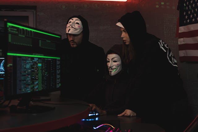 Three hackers gathered around a computer.