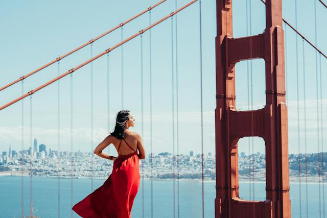 O femeie pozând lângă podul Golden Gate din San Francisco.