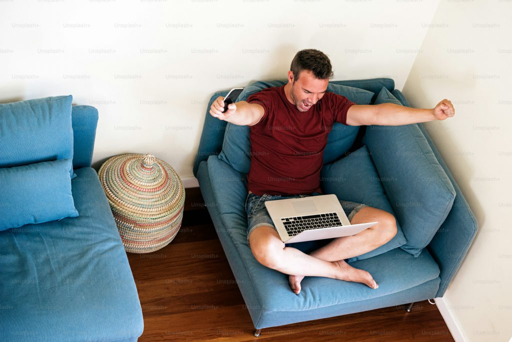 A man on a couch with his laptop looking at his Instagram follower strategy. 