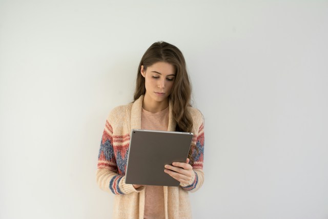 Uma mulher de pé e com um iPad na mão, a percorrer os seus seguidores em Instagram .