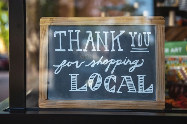 A handwritten sign outside a shop that says, “Thank you for shopping local.”
