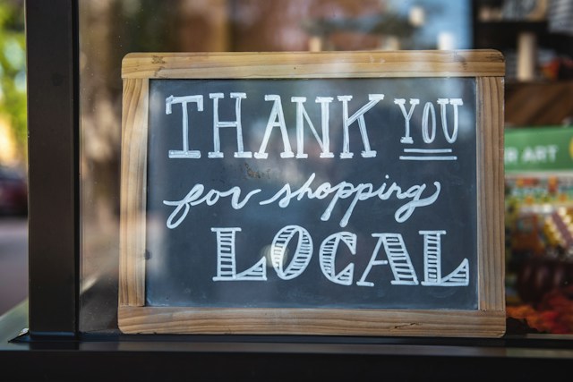 Een handgeschreven bord buiten een winkel met de tekst: "Bedankt voor het lokale winkelen.