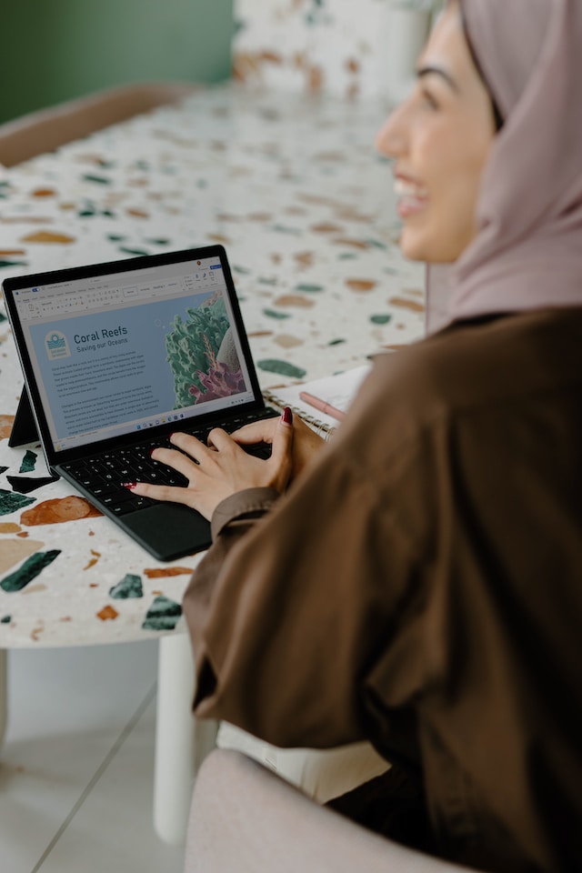 Een vrouw gebruikt haar laptop om de aanwezigheid van sociale media in haar bedrijf te vergroten.