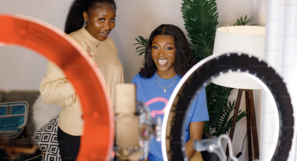 Two women in front of ring lights and recording a video. 