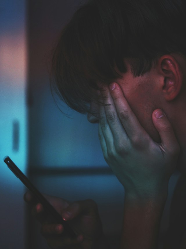 A close-up image of a man holding a phone.