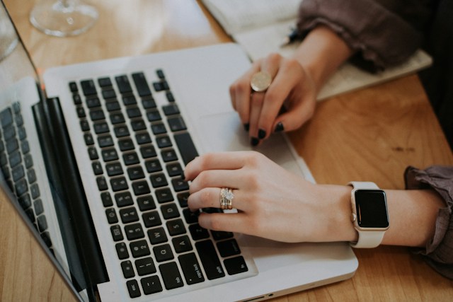 A close-up shot of a woman typing on a laptop.