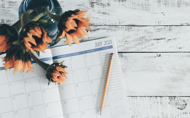 A flat-lay photo of a planner’s monthly calendar and a pencil.