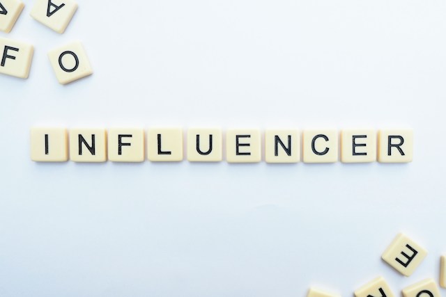The letters of the word "influencer" are spelled using Scrabble tiles. 