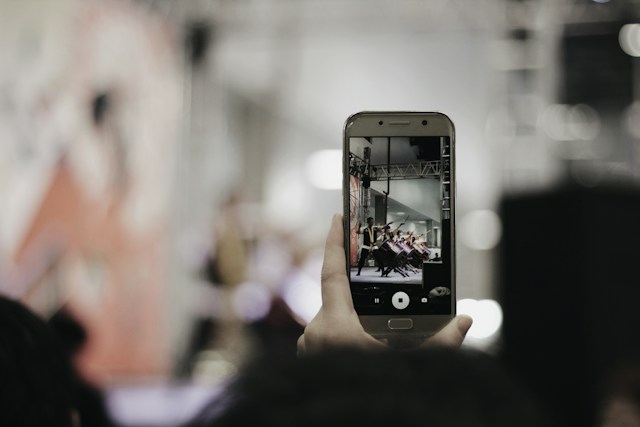 Qualcuno tiene in mano il proprio telefono per riprendere un video di una performance da pubblicare successivamente su Instagram Reels.