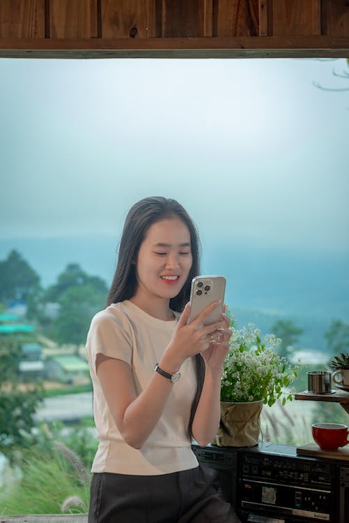 A woman smiling while using her mobile phone.