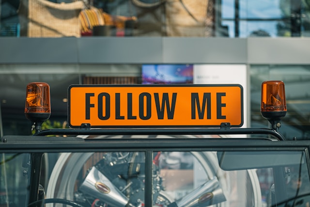 A taxi sign that says, “Follow me,” with siren lights on each side.