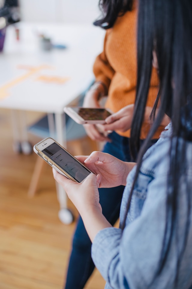 Twee vrouwen kijken naar hun telefoon.