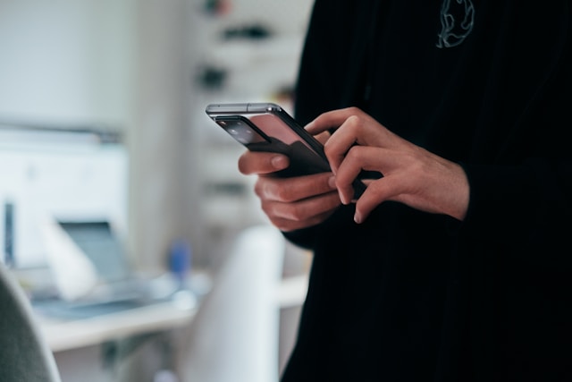 Une femme en noir utilise son téléphone Android.