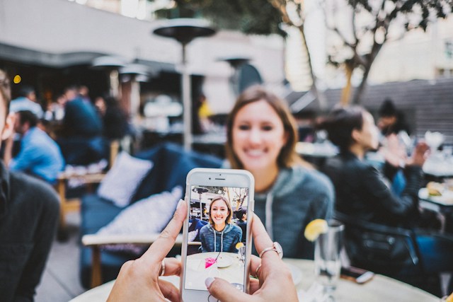 Una persona che riprende un amico al ristorante per i social media.