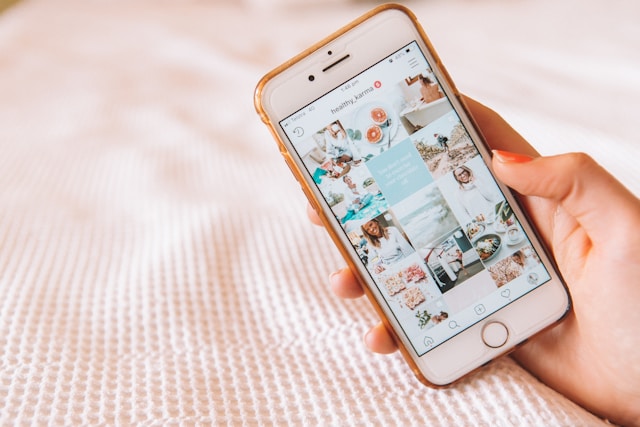 Une personne tenant un iPhone affichant une grille Instagram avec un contenu esthétique.