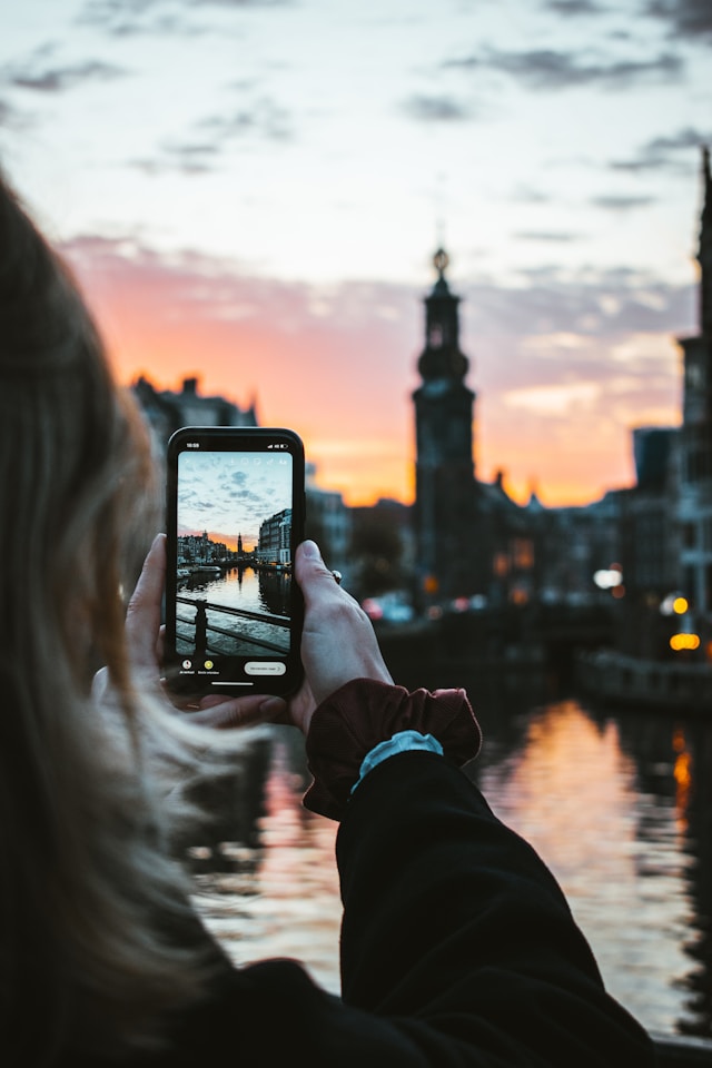 Eine Frau fotografiert ein Gebäude bei Sonnenuntergang. 