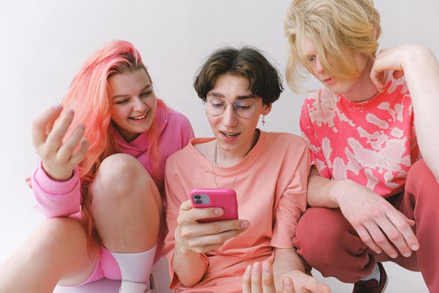 Un grupo de personas vestidas de rosa mirando un smartphone. 