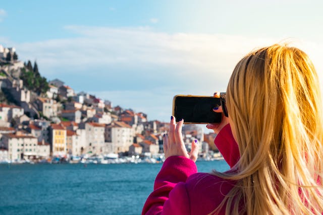 O femeie fotografiază o priveliște pitorească cu ajutorul unui telefon.