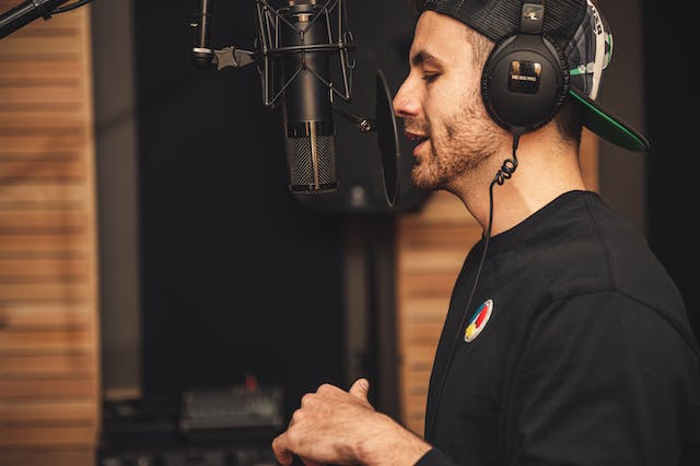  Um homem num estúdio profissional a gravar com um microfone.