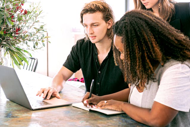 A group of people brainstorming while looking at a laptop. 