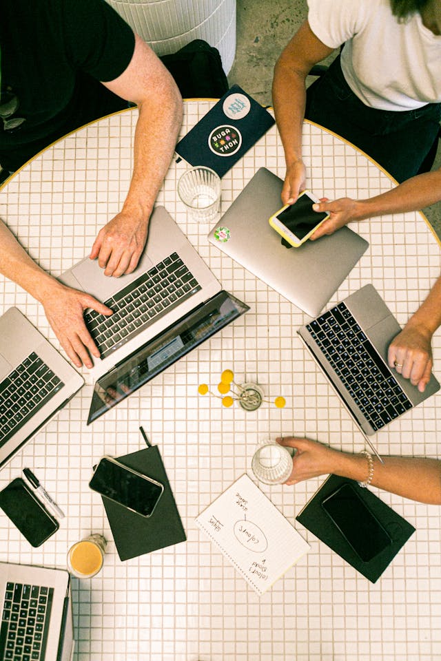 Mehrere Personen arbeiten mit ihren Laptops an einem runden Tisch.