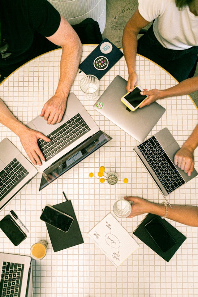 Verschillende mensen gebruiken hun laptop op een ronde tafel.