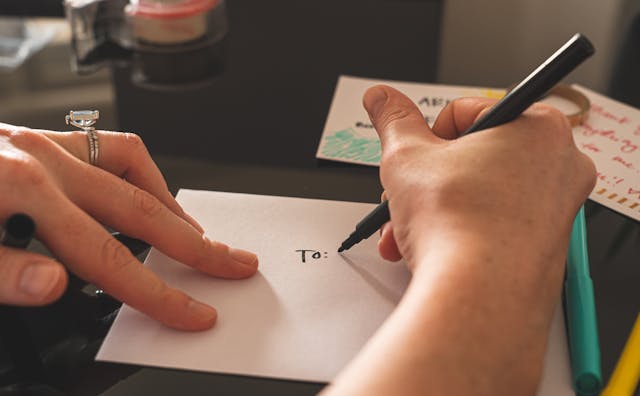  Iemand die "Aan" schrijft op de achterkant van een envelop om naar iemand te sturen.