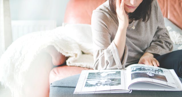 A woman smiling as she looks through old photo albums.