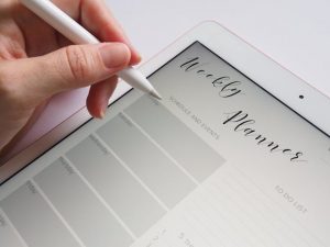 Someone holding a stylus to write notes on a calendar page on a tablet.