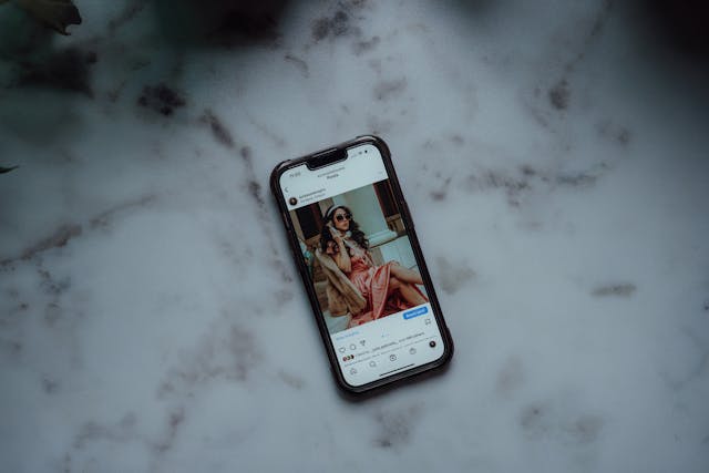 Een telefoon op tafel met een Instagram bericht op het scherm.