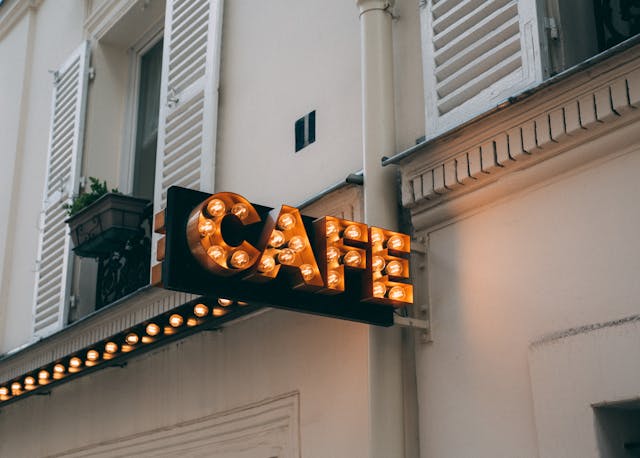 牆上貼著一個發光的標牌，上面寫著“CAFÉ”。