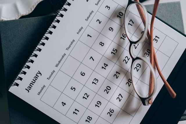 A pair of eyeglasses set down on a monthly calendar.
