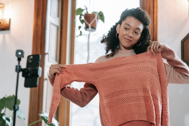セーターの細かいディテールを見せながら自分を撮影する女性。