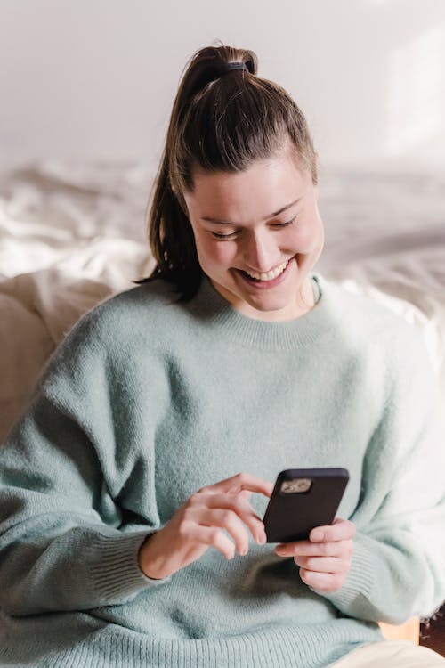 Una chica es feliz mientras se desplaza por su teléfono.