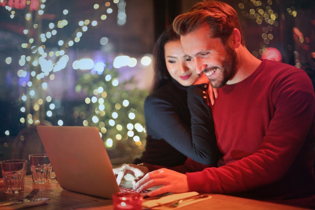 Um homem e uma mulher utilizam o seu computador portátil para fazer compras em Instagram.