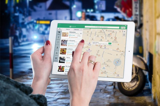 Uma mulher a ver diferentes localizações de restaurantes num mapa no seu iPad.